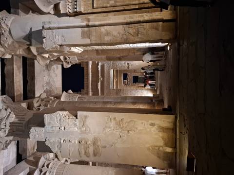       Dramatic nighttime view down a colonnaded hall of an ancient Egyptian temple lit by spotlights.
  