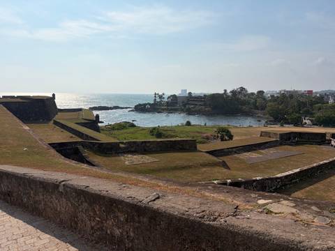       View of Galle Fort ramparts overlooking the Indian Ocean and a rocky inlet.
  