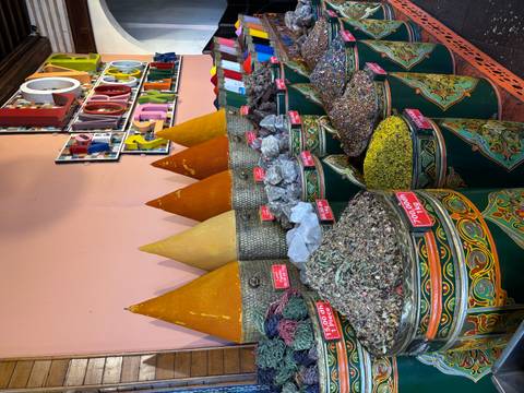       Colorful cones of spices, dried herbs and minerals displayed in ornate metal barrels inside a Moroccan shop.
  