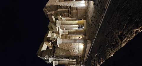       Illuminated columns and reliefs of an ancient temple standing against night sky
  