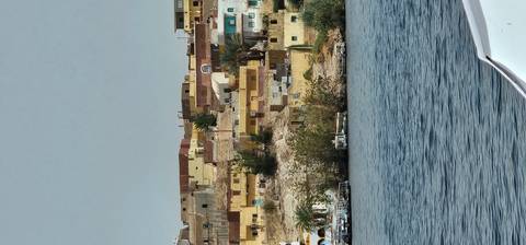       Colorful hillside village of flat-roofed houses overlooking a wide river
  