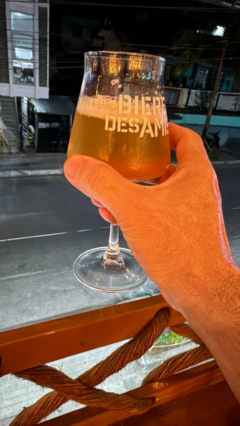       Hand holding an amber cocktail in a stemmed glass against a city street backdrop.
  