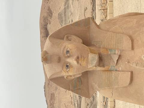       Close-up of an ancient Pharaoh statue with desert hills in the background.
  