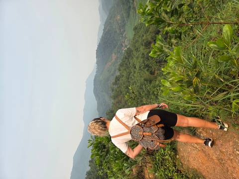       Hiker with backpack surveys rolling green mountains from a narrow dirt ridge.
  