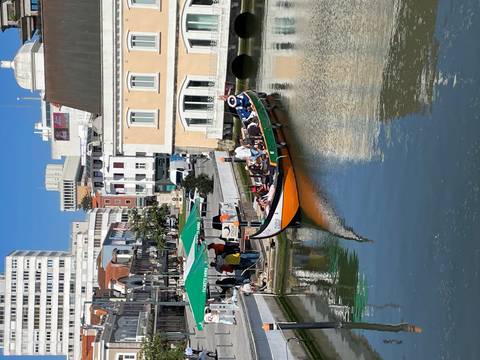       Traditional moliceiro boat full of passengers gliding along Aveiro’s canal under clear blue skies.
  