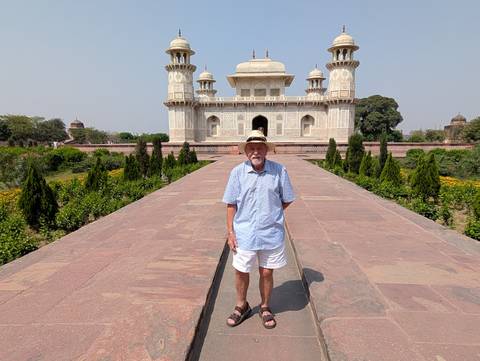       Traveller posing in front of Itimad-ud-Daulah marble mausoleum in Agra gardens
  