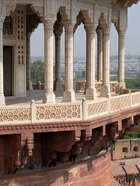       Detailed view of carved marble columns and geometric latticework at Itimad-ud-Daulah with river bridge in distance
  
