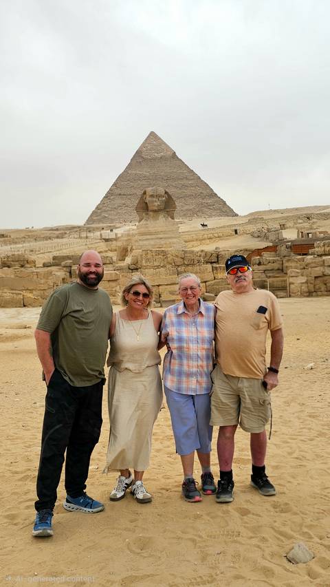       Four travellers pose arm-in-arm with the Great Sphinx and a pyramid looming behind them.
  