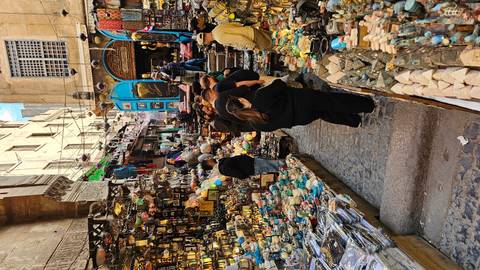       A bustling bazaar alley packed with souvenir stalls, magnets, and visitors browsing vibrant trinkets.
  