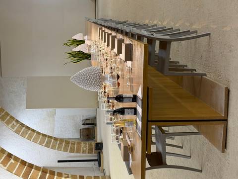       Long wooden table set with rows of wine glasses and bottles in an elegant tasting room with arched stone walls.
  