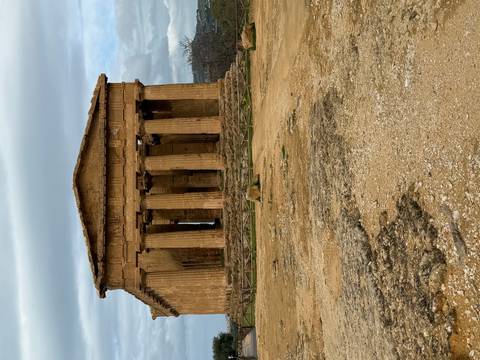       Well-preserved Greek temple with sturdy Doric columns stands on a rocky plateau under moody skies.
  