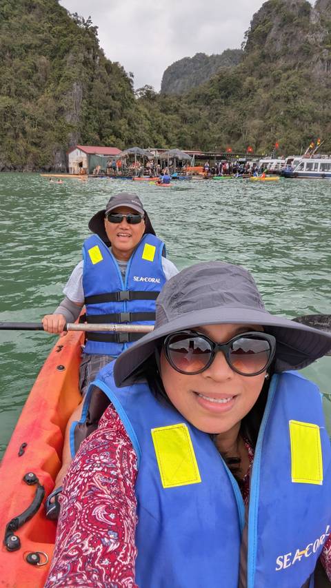       Selfie on a kayak with emerald water and limestone peaks visible behind.
  