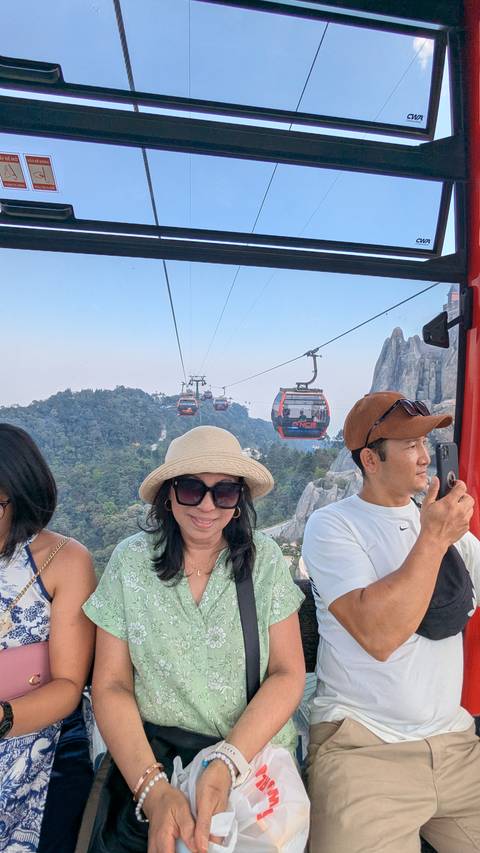       Travellers riding a cable car with rocky peaks of Ba Na Hills around them.
  