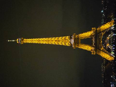       Illuminated Eiffel Tower glowing gold against the dark night sky.
  