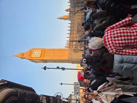       Crowds gather near Big Ben and the Houses of Parliament bathed in warm evening light.
  