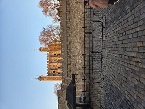       Sunlit medieval stone fortress tower behind crenellated walls at the Tower of London.
  