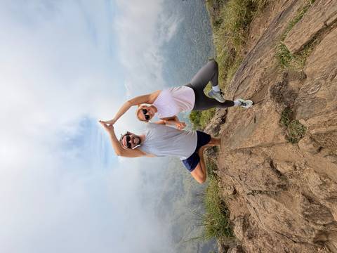       Fit couple strikes a playful yoga pose atop a misty mountain viewpoint.
  