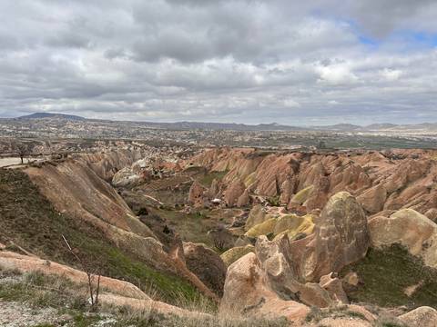       Expansive view over Cappadocia’s multicoloured ridges and valleys under a brooding sky.
  