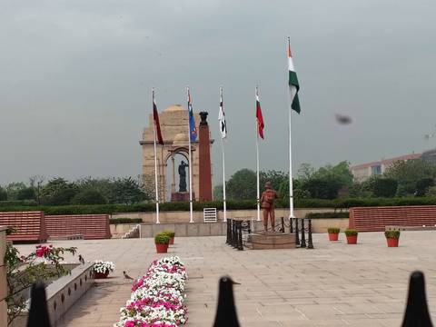       National War Memorial courtyard with flags and statues under a gray sky.
  