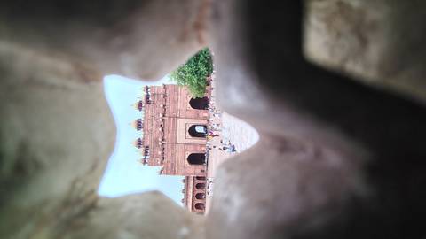       View of Buland Darwaza seen through a jagged stone opening creating a natural frame.
  