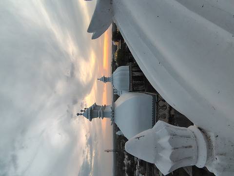       White rooftop domes with decorative finials against a dramatic sunset sky.
  