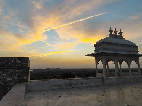      Silhouette of a pavilion dome on a rooftop terrace against pastel dawn clouds.
  
