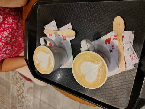       Two cappuccinos with heart-shaped latte art on a café tray.
  