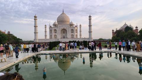       Crowds gather in front of the reflecting pool at the Taj Mahal, capturing its full symmetry.
  