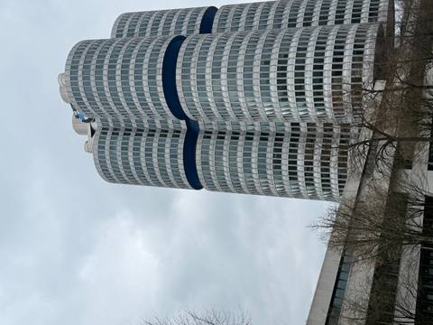       Modern cylindrical BMW Headquarters tower rising against a grey cloudy sky.
  