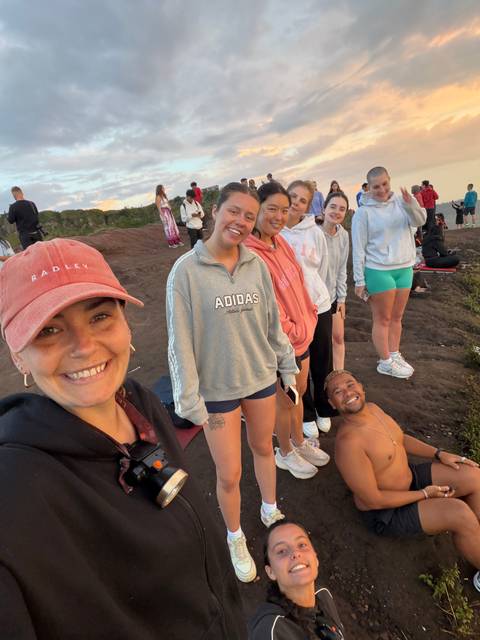       Travellers line a volcanic rim at dawn, smiling for a selfie with misty valleys behind them.
  