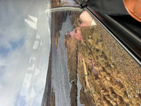       A bleak moorland loch viewed through a coach window with distracting reflections.
  