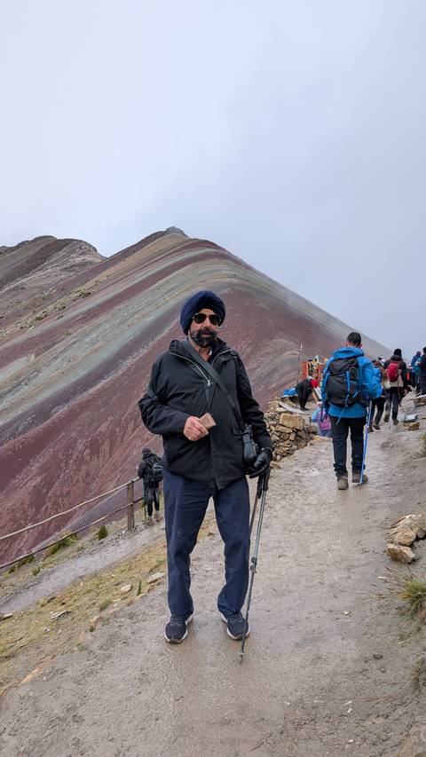       Trekkers ascend the colourful slope of Rainbow Mountain with a foreground portrait of a hiker.
  