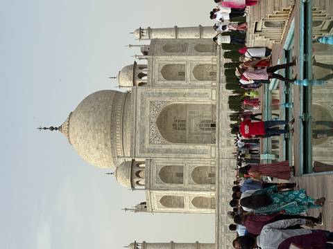       Iconic view of the Taj Mahal with reflecting pools and crowds of visitors in the foreground.
  