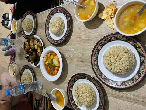       Low table spread with bowls of soup, rice domes and grilled chicken for a desert camp meal.
  