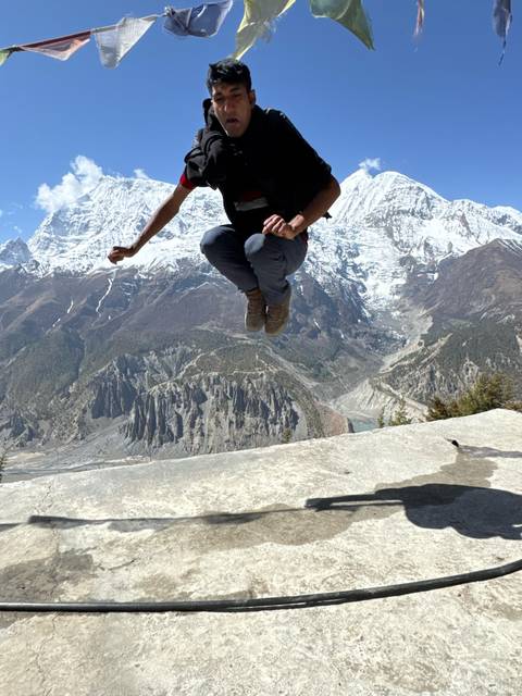       Hiker caught mid-air jump against dramatic snow-capped Himalayan peaks and deep valleys.
  