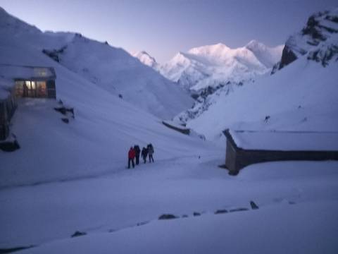       Dark, blurry image of trekkers ascending snowy slope before dawn.
  