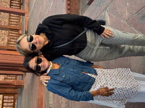       Two women wearing sunglasses pose together in courtyard of historic fort.
  