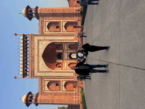       Couple poses on broad pathway before grand Mughal gateway leading to the Taj Mahal.
  