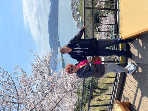       Couple posing with blooming cherry blossoms and a sparkling bay below.
  