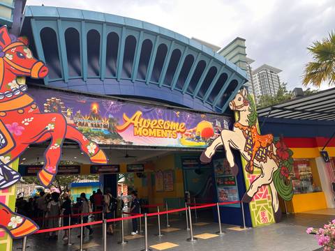       Entrance to an amusement park with carousel horses and banner reading 'Awesome Moments'.
  
