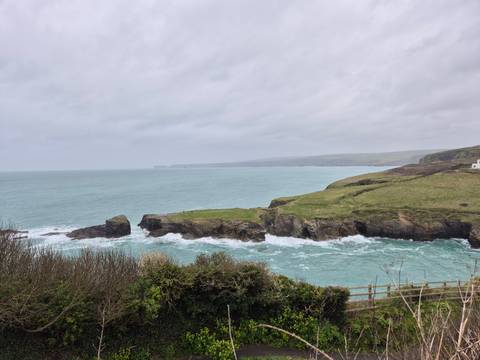       Turquoise sea breaking against rocky headlands under an overcast sky along the Cornish coast.
  