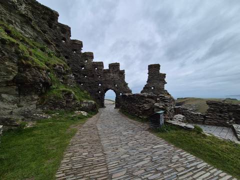       Stone path leads through the dramatic ruins of Tintagel Castle perched on a clifftop.
  