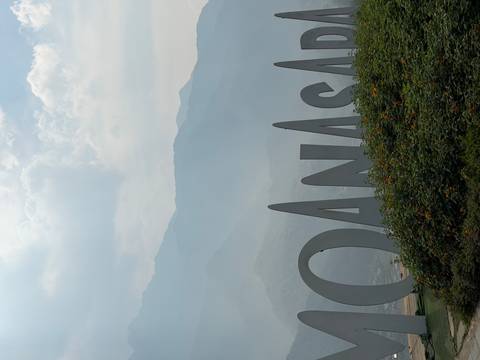       Misty mountain backdrop behind large sculptural letters in a landscaped garden.
  