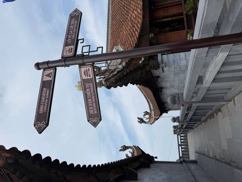       Directional signposts pointing to Fansipan summit and pagoda against temple rooftops.
  