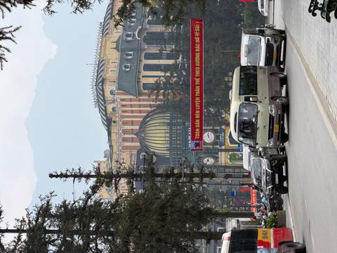       Busy streetscape in Sapa with vehicles, alpine style buildings and mountains shrouded in haze.
  