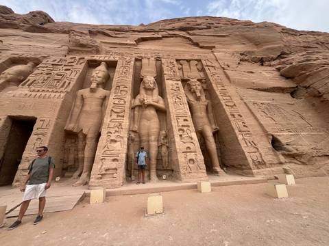       Travelers pose in front of the smaller temple façade at Abu Simbel with colossal statues
  