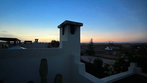      Subtle dusk sky behind a white rooftop chimney and silhouettes of distant countryside
  