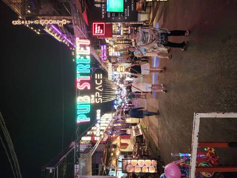       Vibrant nightlife scene on Pub Street with neon signs and tourists strolling between bars and eateries.
  