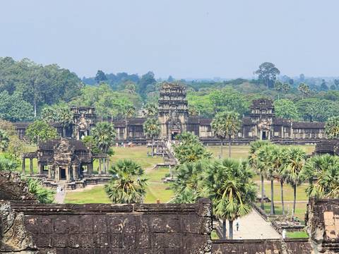       Expansive view of Angkor Wat’s ancient stone temples surrounded by lush greenery.
  