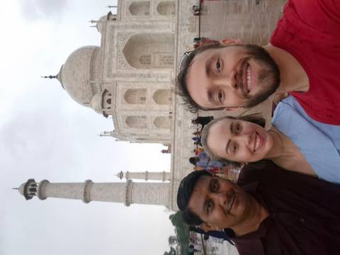       Smiling travellers taking a selfie in front of the Taj Mahal’s iconic marble dome.
  